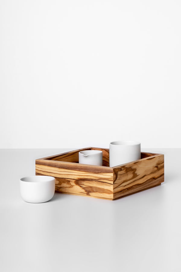 A rectangular olive wood serving tray with three compartments, featuring a natural grain pattern, used to present two white cups.