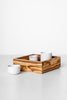 A rectangular olive wood serving tray with three compartments, featuring a natural grain pattern, used to present two white cups.