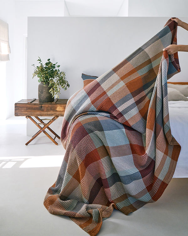 Person putting 100% cotton blanket on bed.
