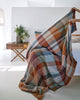 Person putting 100% cotton blanket on bed.