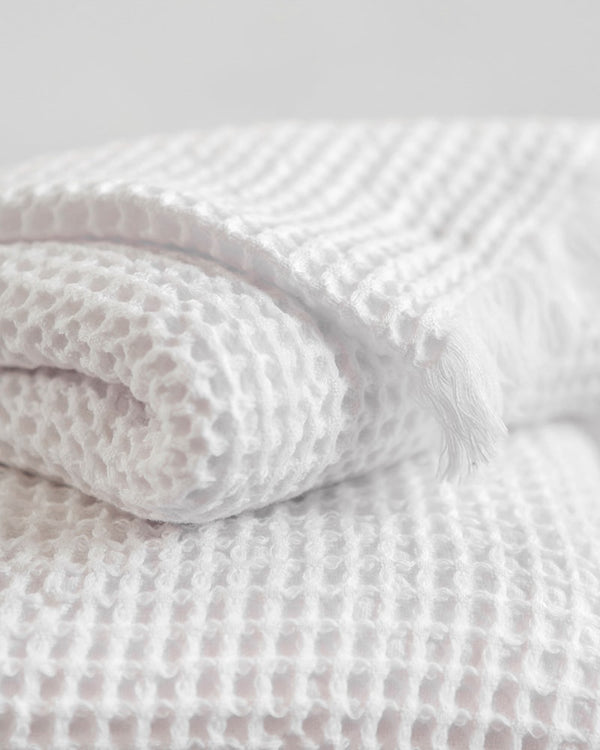 A folded white organic cotton Belgian waffle bath towel displaying its textured waffle weave pattern.