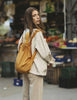 Woman with a yellow backpack standing in an outdoor market setting