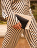 Person wearing a black and white striped outfit holding a clutch.