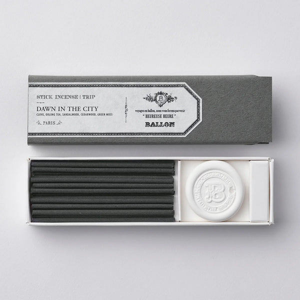 Incense sticks and a round incense burner in a gray box on a light gray background