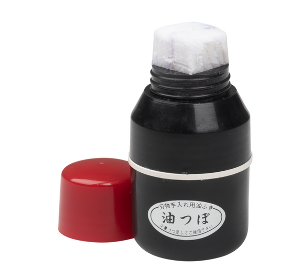 A black Niwaki oil dispenser with a red cap, designed for applying camellia oil to tools to prevent rust.