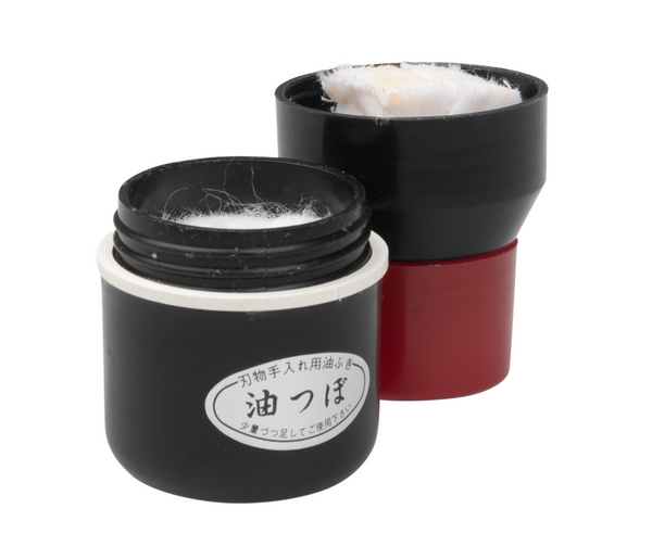A black Niwaki oil dispenser with a red cap, designed for applying camellia oil to tools to prevent rust.