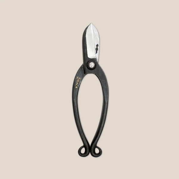 Black-handled shears with a metallic blade on a beige background