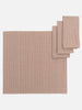A collection of brown and white hand-dyed cotton table linens, including a tablecloth and napkins, displayed on a white background.