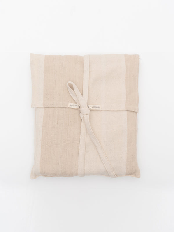 A striped peach and pink cotton throw blanket with fringes and a matching pouch, displayed neatly folded.