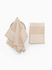 Two beige kitchen towels, one folded and one hanging, on a white background.