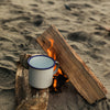 Camping scene with a mug on a small fire built into the sand.