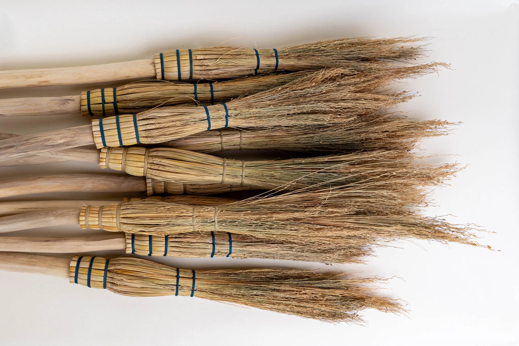 Set of brooms with straw bristles on a white background