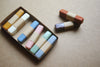 Set of colorful pastel crayons in a box on a beige surface