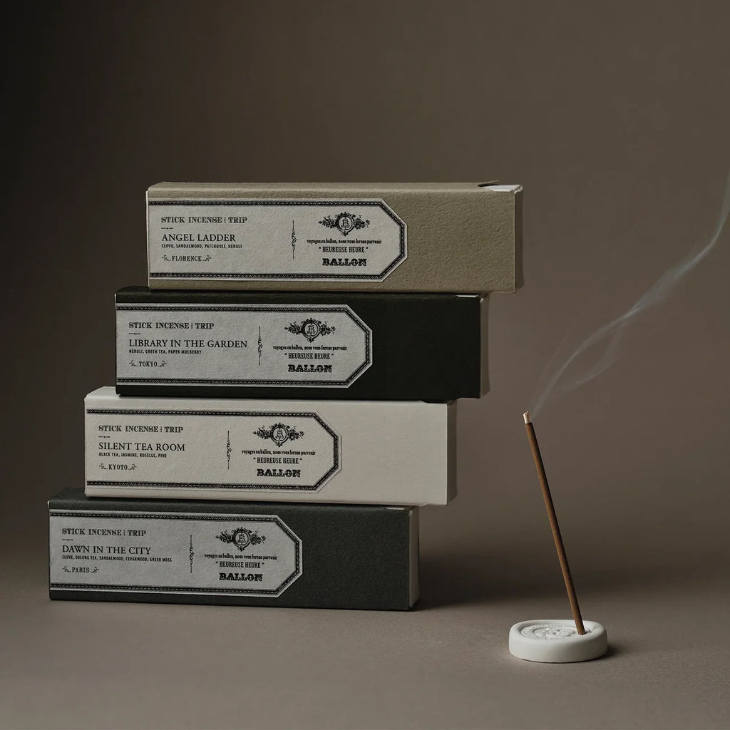 Stack of incense boxes with a smoking incense stick on a dark background