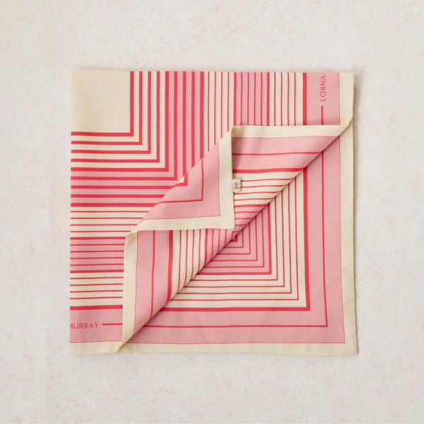 A folded scarf with a geometric stripe pattern in rose pink, cherry red, and clotted cream colors, displaying the Lorna Murray brand name.