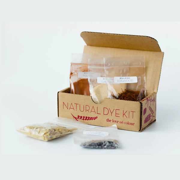 A cardboard Natural Dye Kit box shown open with several clear plastic bags containing dye ingredients and materials, photographed on a clean white background.