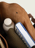 Brown leather bag with a bottle, book, and knitted item inside