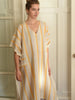 Woman wearing a striped dress with yellow and beige colors against a neutral background