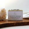A bar of natural soap with placed on a wooden surface with decorative elements around it.