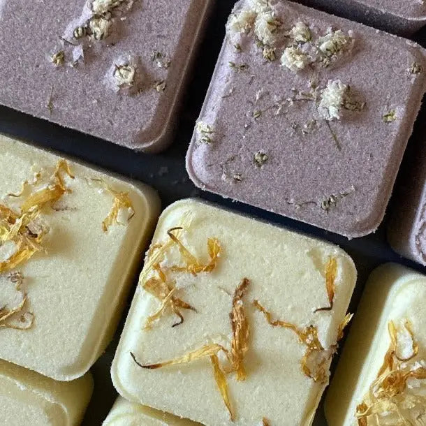Several bath bombs with a beige exterior and a piece of orange rind on top, indicating a citrus scent.