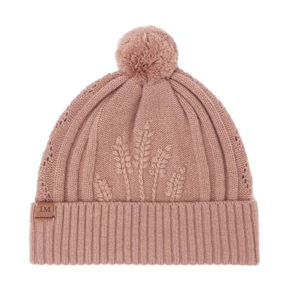 Blush pink knit beanie with embroidered leaves and a pom-pom on a white background