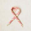 A looped scarf with a geometric stripe pattern in rose pink, cherry red, and clotted cream colors.
