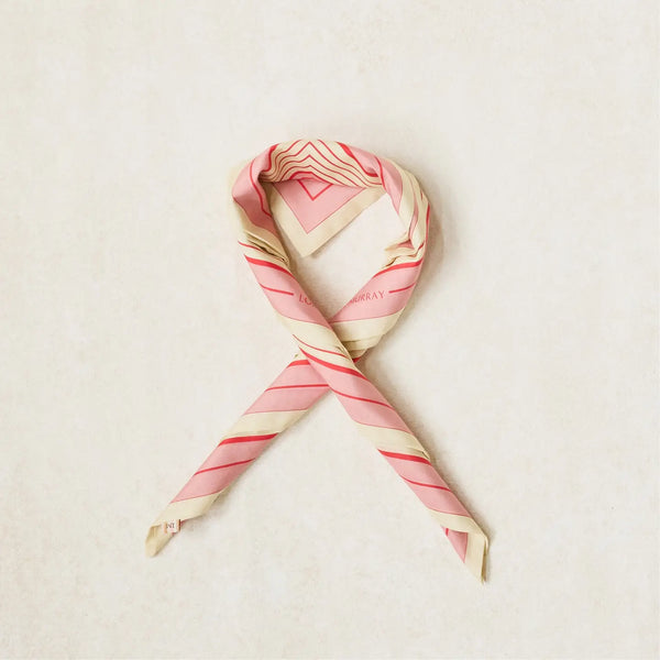A looped scarf with a geometric stripe pattern in rose pink, cherry red, and clotted cream colors.