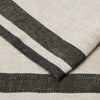 A close-up of a woven textile with a cream base and bold black horizontal stripes, showing the fabric texture and fold detail.