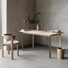 Minimalist office setup with a wooden desk, chair, and decor against a brick wall.