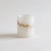 A cylindrical alabaster votive candle holder with subtle color variations, placed on a white background.