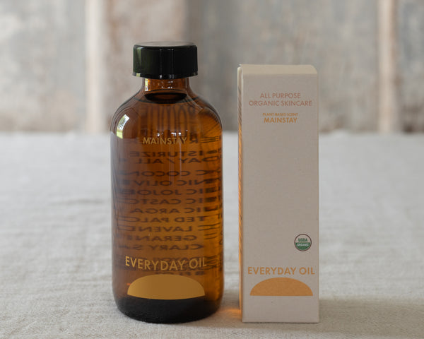 Bottle and box of Mainstay Everyday Oil on a textured surface with a blurred background