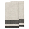 Two folded woven towels in a light oatmeal beige color with a dark charcoal gray and white striped border, displayed on a solid white background.