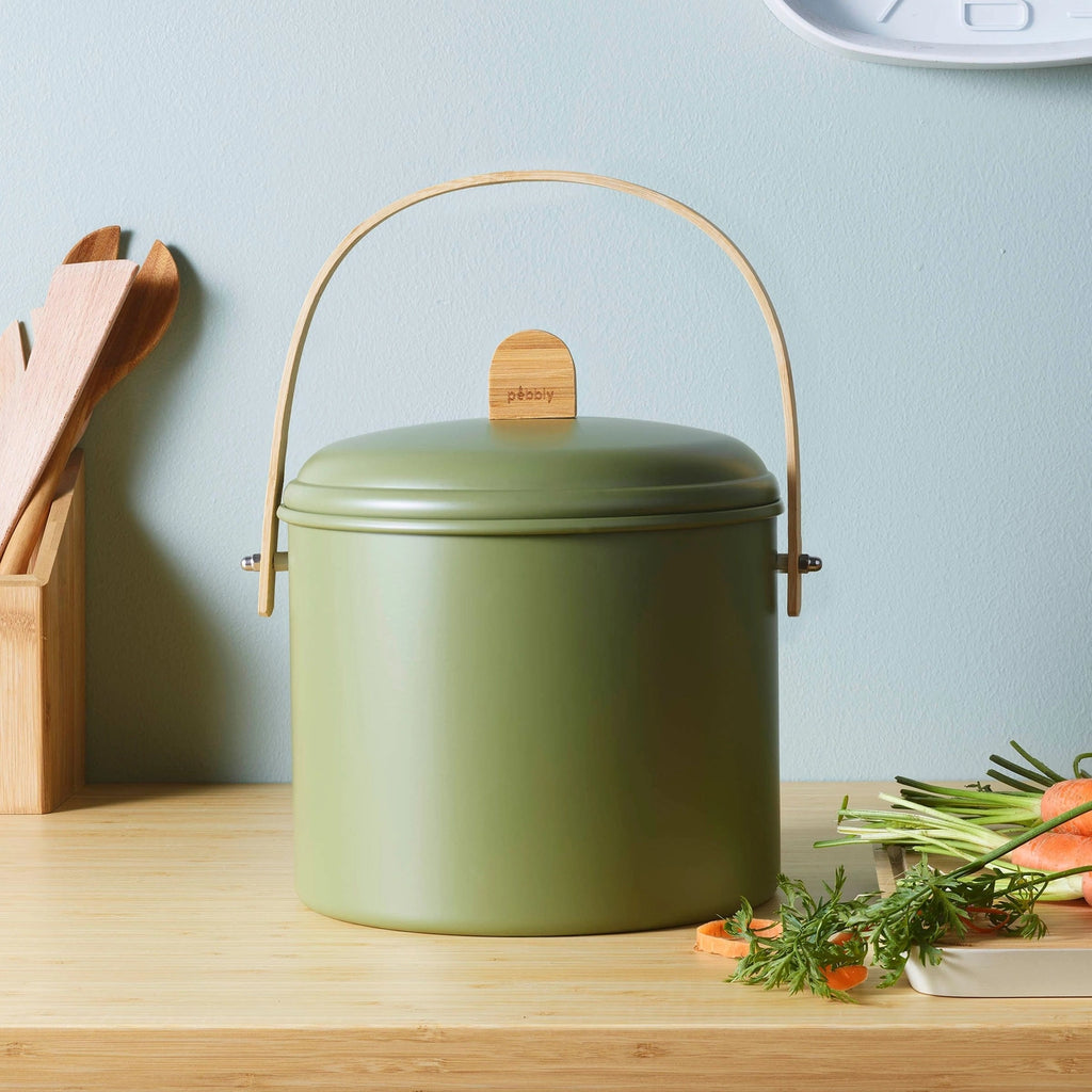 Green compost bin with wooden handle on a kitchen counter