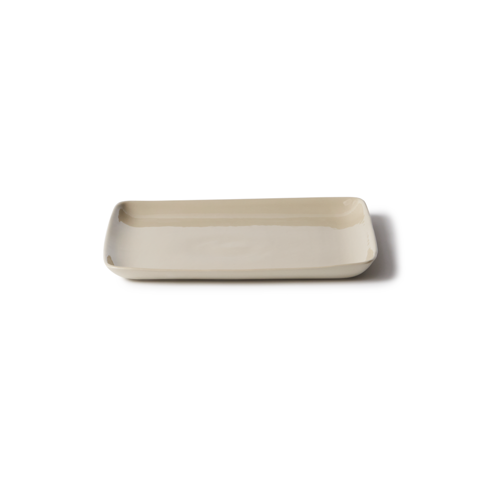A rectangular ceramic serving platter with rounded corners in a light beige color, shown on a plain white background with a soft shadow.
