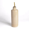 Beige ceramic bottle with gold cap on a white background