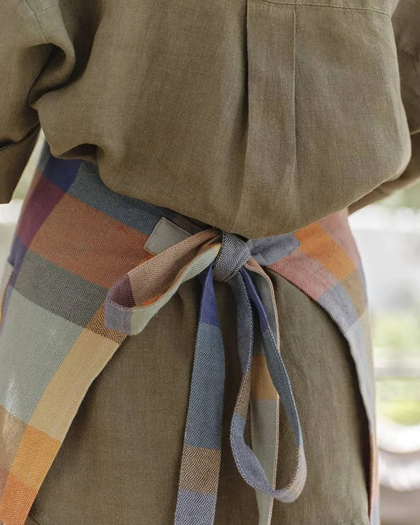 Person wearing a plaid apron with a blurred background