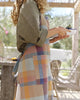 Person wearing a colorful checkered apron in an outdoor setting
