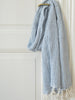 Blue and white checkered towel with tassels hanging on a white door.