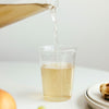 A liquid being poured from a CAST collection glass pitcher into a clear CAST Collection cup.