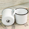 Two white enamel mugs with black rims on a wooden surface