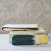A collection of soft wool pencil cases in grey, green, and yellow, stacked together.