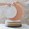 A collection of round wool seat cushions in various colors stacked on a white table.