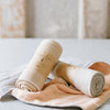 A rolled up beige fitness towel with a label on it, placed on a light-colored surface, possibly indicating the product's brand or information.