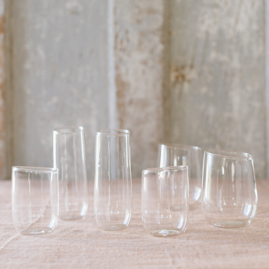 A selection of clear glassware pieces displayed on a surface, including various shapes and sizes of glasses and a pitcher.