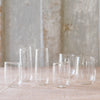 A selection of clear glassware pieces displayed on a surface, including various shapes and sizes of glasses and a pitcher.
