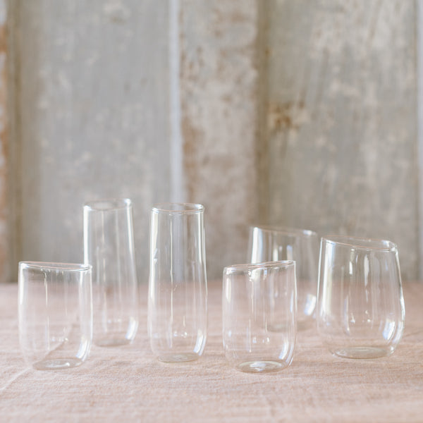 A selection of clear glassware pieces displayed on a surface, including various shapes and sizes of glasses and a pitcher.
