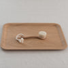 A beige wooden face brush with goat hair bristles, displayed on a wooden surface with a white background.