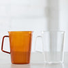 Two elegant glassware pitchers, one amber and one clear.