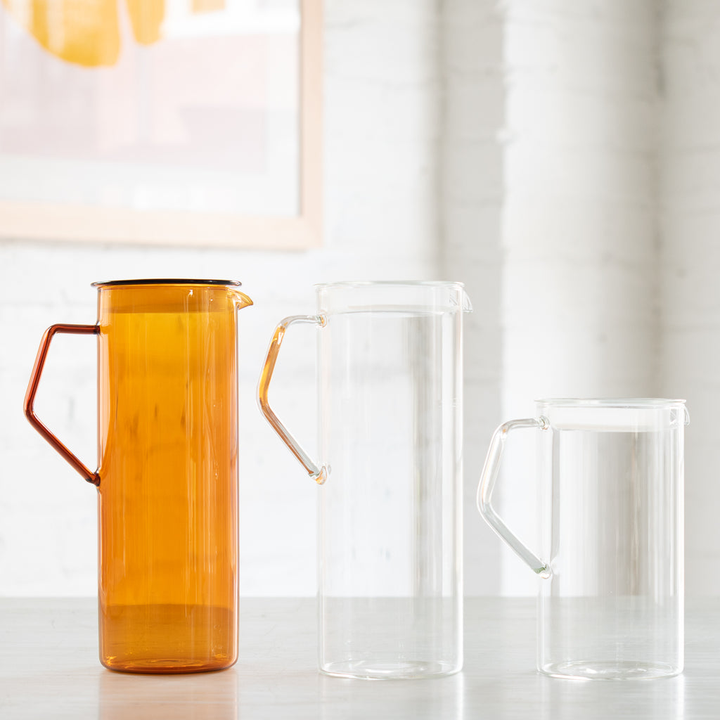 Three different glassware pitchers. One is amber, and two are clear.