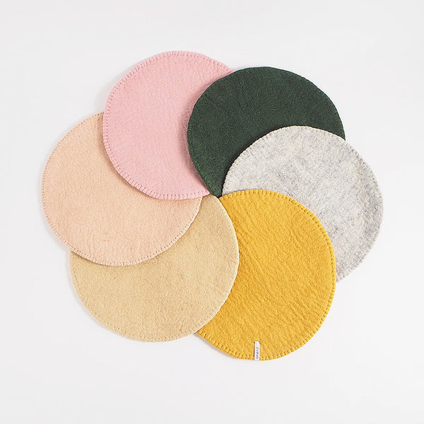 A collection of round wool seat cushions in various colors arranged together.
